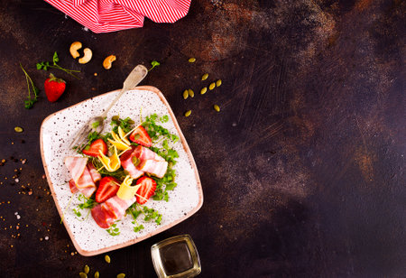 Assorted cheeses and prosciutto with strawberry on plateの写真素材