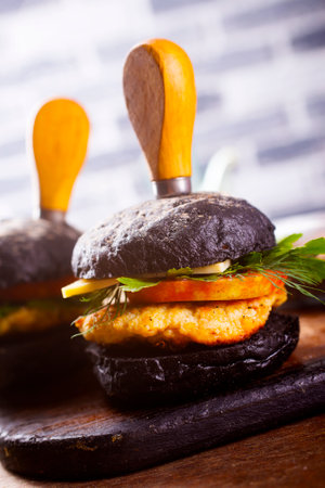 Tasty craft burger with black bun on the boardの写真素材