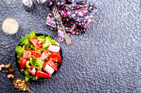 salad with ham and tomato on black plateの写真素材