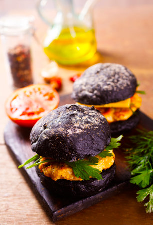 Tasty craft burger with black bun on the boardの写真素材