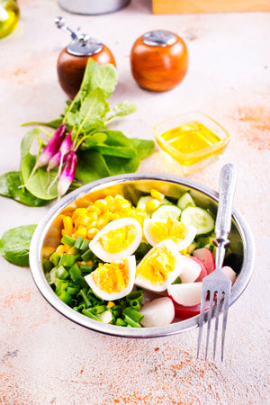 Bowl of vegetarian salad with boiled eggs- radishes- cucumbers- corn saladの写真素材