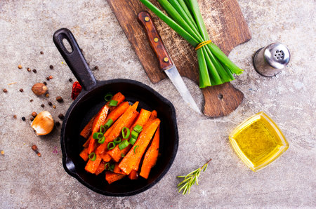 Fried carrots with green herbs in baking tray, close upの写真素材