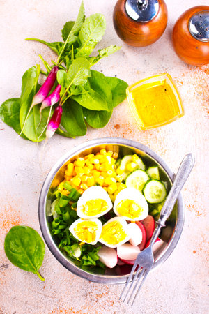 Bowl of vegetarian salad with boiled eggs- radishes- cucumbers- corn saladの写真素材