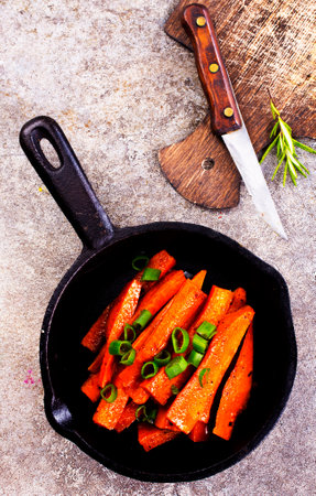 Fried carrots with green herbs in baking tray, close upの写真素材