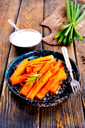 Fried carrots with green herbs in baking tray, close upの写真素材
