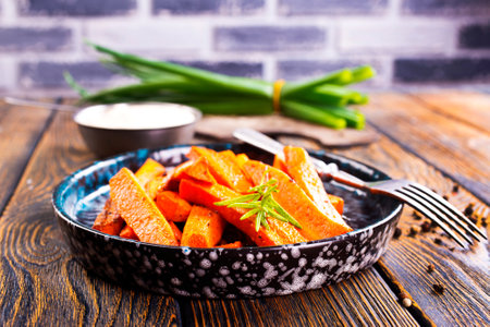 Fried carrots with green herbs in baking tray, close upの写真素材