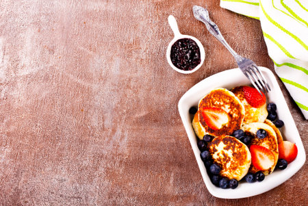 Cottage cheese pancakes with raspberries and blueberries on light background, breakfast or lunchの写真素材