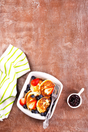 Cottage cheese pancakes with raspberries and blueberries on light background, breakfast or lunchの写真素材