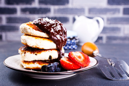 Traditional syrniki served with fresh strawberries, blueberry, mint leaves, drizzled with chocolateの写真素材