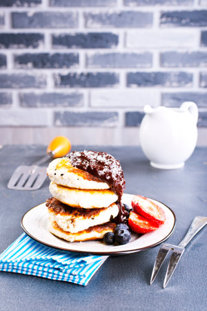 Traditional syrniki served with fresh strawberries, blueberry, mint leaves, drizzled with chocolateの写真素材