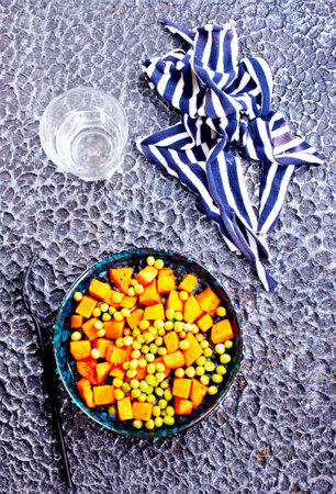 Peas and carrots in a black salad bowlの写真素材