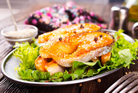 Fried salmon steak with spice vegetables on wooden tableの写真素材