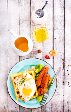 Delicious breakfast. Served on a wooden table with toast, eggs, sausage, wafers, juice. Top view.の写真素材