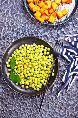 Peas and carrots in a black salad bowlの写真素材