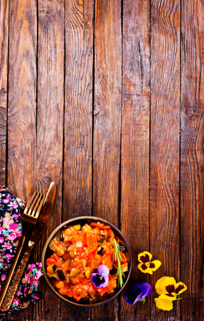 vegetable stew, eggplant, onion, zucchini with tomato sauce, garlic and herbs in a baking dish on a wooden table, landscape view from above, close-up, flat lay, free spaceの写真素材