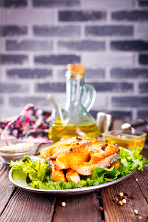 Fried salmon steak with spice vegetables on wooden tableの写真素材