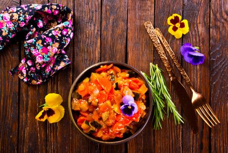 vegetable stew, eggplant, onion, zucchini with tomato sauce, garlic and herbs in a baking dish on a wooden table, landscape view from above, close-up, flat lay, free spaceの写真素材