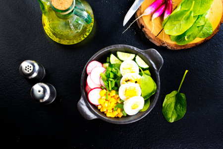 Bowl of vegetarian salad with boiled eggs- radishes- cucumbers- corn saladの写真素材