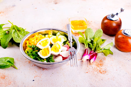 Bowl of vegetarian salad with boiled eggs- radishes- cucumbers- corn saladの写真素材