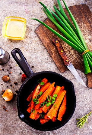 Fried carrots with green herbs in baking tray, close upの写真素材