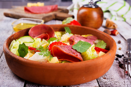 fresh salad with salami and vegetables on a plateの写真素材