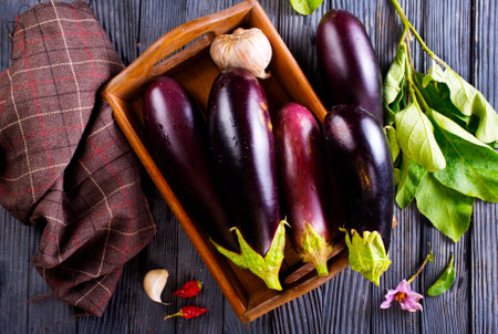 raw eggplants in wooden box on dark tableの写真素材