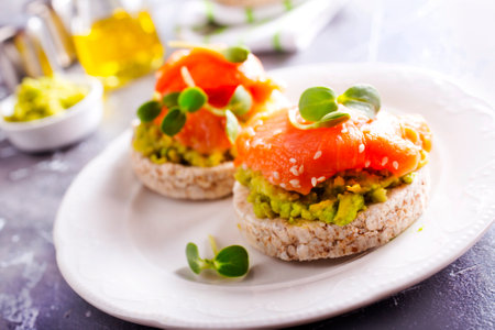 diet sandwiches with rye bread, avocado, smoked salmon on a white plateの写真素材
