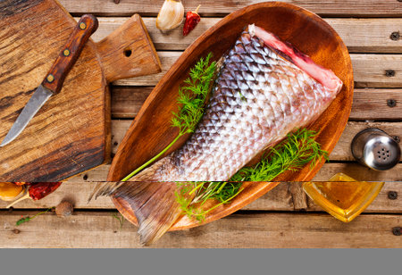 fresh fish with green dill and spice on wooden plateの写真素材
