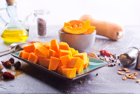 Diced pumpkin pieces in a bowl, with spices and olive oilの写真素材