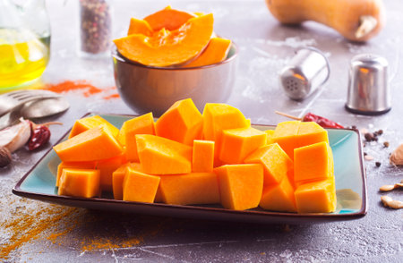 Diced pumpkin pieces in a bowl, with spices and olive oilの写真素材