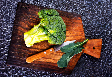 fresh green broccoli on wooden cutting board with knife. Broccoli cabbage leaves.の写真素材