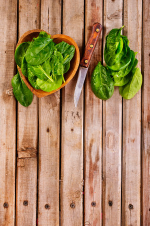 Fresh spinach leaves in bowl on rustic wooden table.の写真素材