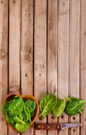 Fresh spinach leaves in bowl on rustic wooden table.の写真素材