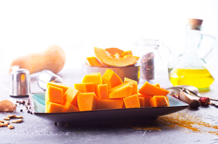 Diced pumpkin pieces in a bowl, with spices and olive oilの写真素材