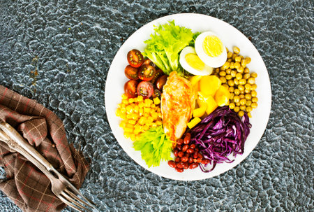 Salad on plate, healthy food consisting of lettuce, tomatoes, corn, carrot, boiled egg, smoked chickenの写真素材