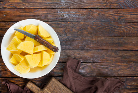 fresh raw potato slices on rustic wooden kitchen table, top viewの写真素材