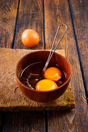 Bowl with raw egg yolk on wooden tableの写真素材