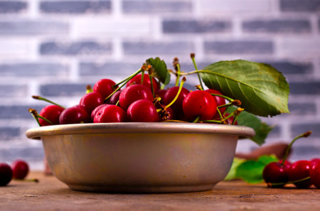 fresh cherry with leaves in metal bowlの写真素材