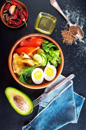 Delicious healthy brunch - boiled egg, smoked salmon, green salad and savory pancakes on a dark backgroundの写真素材