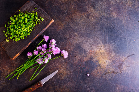 Green chives or allium in bloom with purple violet flowers and green stems on a wooden table, Chives is a edible herb for use in the kitchen.の写真素材