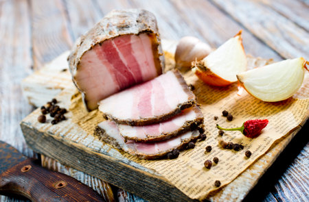 Smoked lard, bacon, half a piece, on a wooden dark craft board. Top viewの写真素材