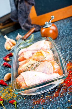 Raw chicken drumsticks with seasonings in glass plate. Chicken legs ready to cook. Organic meat, healthy eating conceptの写真素材