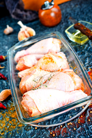 Raw chicken drumsticks with seasonings in glass plate. Chicken legs ready to cook. Organic meat, healthy eating conceptの写真素材