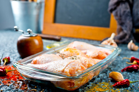 Raw chicken drumsticks with seasonings in glass plate. Chicken legs ready to cook. Organic meat, healthy eating conceptの写真素材