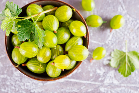 fresh organic gooseberries in a wooden bowl on a tableの写真素材