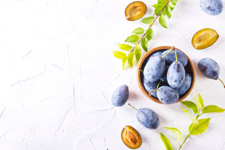 fresh plum fruit in bowl on white tableの写真素材