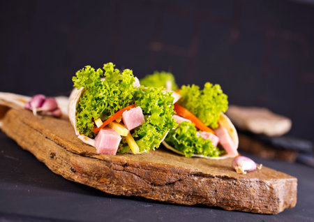 Fresh tortilla wraps with ham cheese and vegetables on stone boardの写真素材