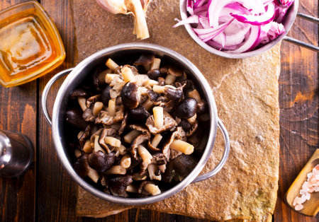 pickled mushrooms in metal bowl on the table, next to spices.の写真素材