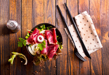 Sliced Pastrami roasted beef meat with vegetables. Wooden backgroundの写真素材