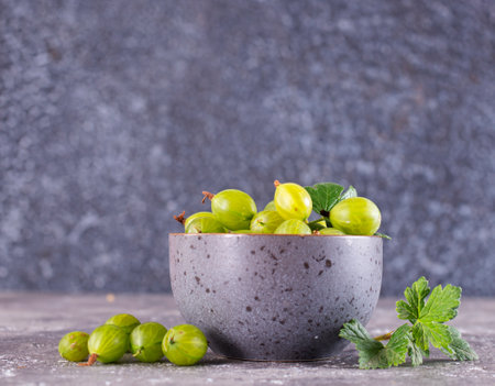 Fresh gooseberry in gray bowl on a table, green gooseberryの写真素材